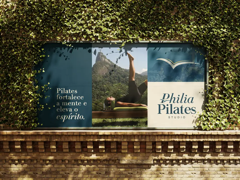 Banner da Philia Pilates em muro externo, com exercício de Pilates diante do Cristo Redentor
